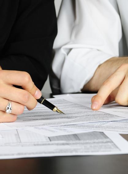 Two people are dicussing something and pointing at some papers on a table in front of them.